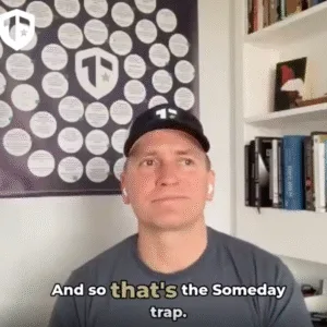 Coach Brandon Jenkins writes about the Someday Trap. He's pictured in his office, wearing a navy blue baseball cap with the Tier One logo.